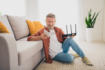 Full size photo of senior male sit floor read instruction confused fix wifi dressed brown outfit...
