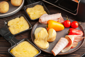 Delicious traditional Swiss melted raclette cheese on diced boiled or baked vegetables served in individual skillets