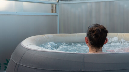 Young woman seen from behind bathing inside an inflatable jacuzzi