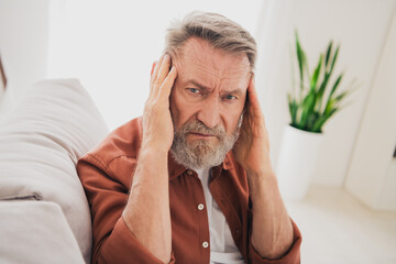 Photo of nice retired man sit couch touch temples suffer headache wear brown clothes modern cozy interior flat indoors