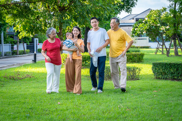 Fototapeta premium Asian family and baby are in the grass. Everyone looks happy.