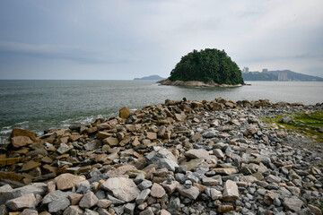 View from the rocks of the breakwater to the Urubuquecaba Island of Santos, coastal city of the interior of Sao Paulo, SP, Brazil.