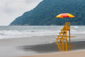 An empty lifeguard chair in front of a tourist beach that has strong waves. Tombo beach, Guaruja - SP- Brazil.
