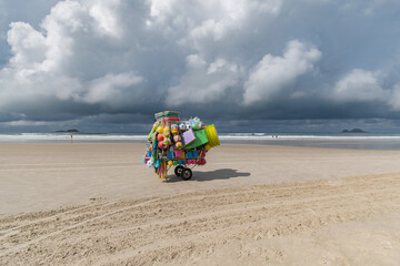 Street vendor cart selling beach items such as surfboards and children's toys on Enseada beach, Guaruja - SP, Brazil.