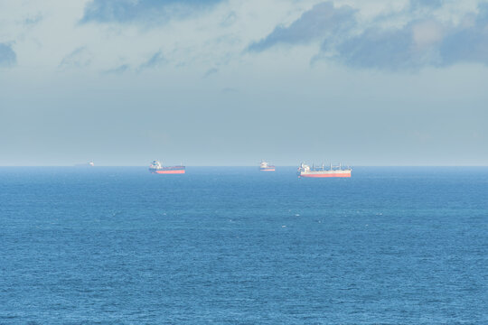 Cargo ships seen far away from the coast in the middle of the sea.