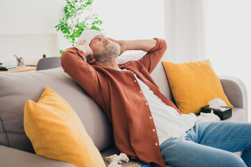 Photo of nice retired man sit couch towel compress high temperature wear brown clothes modern cozy...
