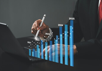 Businessman sits with pen touching virtual screen, annual financial report, chart with annual...