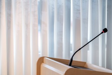 A microphone placed on a wooden podium against a backdrop of vertical blinds