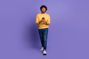 Photo of cheerful young man wear trendy yellow clothes hold use gadget isolated on purple color...