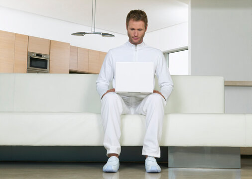 Portrait of Man Sitting on Sofa, Using Laptop