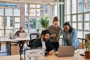 Diverse group of focused businesspeople working on a laptop