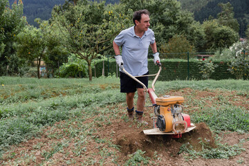 Man using tiller in vegetable garden