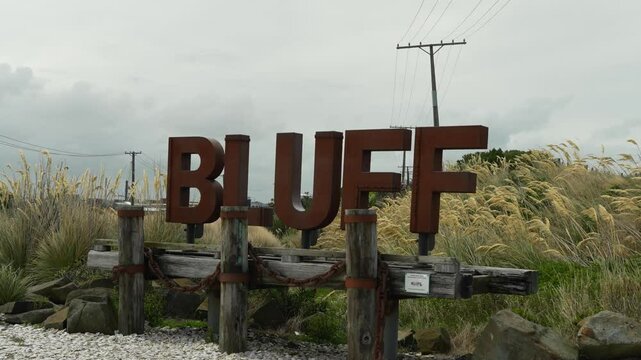 Rusty metal Bluff town sign on gorund coverd with fmaous bluff oysters with long grass.