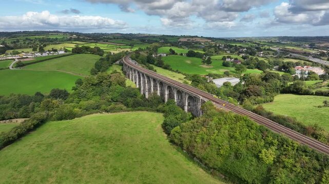 Craigmore Viaduct, County Armagh, Northern Ireland, September 2022. Drone pushes forward and orbits counter clockwise around the Victorian Railway Bridge outside Newry bathed in warm sunlight.