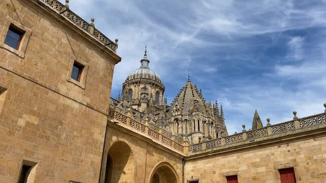 filming of a part of the Salamanca cathedral where we can see a beautiful Gothic-style stone balustrade and we can see the domes of the old cathedral with a background of a blue sky with light clouds
