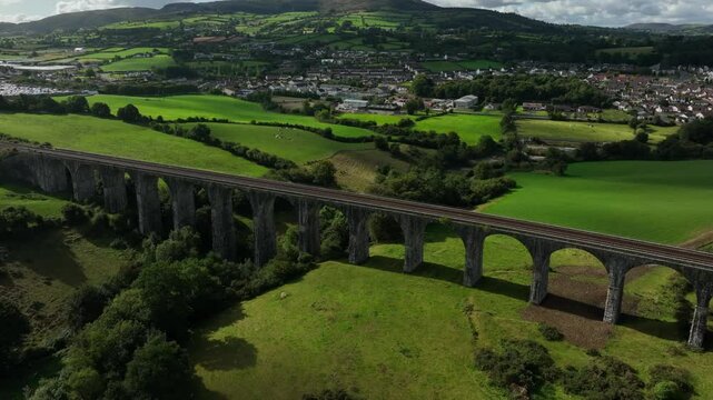 Craigmore Viaduct, County Armagh, Northern Ireland, September 2022. Drone orbits counter clockwise around 19th century Railway Bridge above rural pasture with stunning views of Newry and mountains.