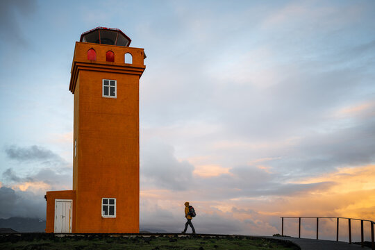 man standing in front of orange lighthouse in Iceland
