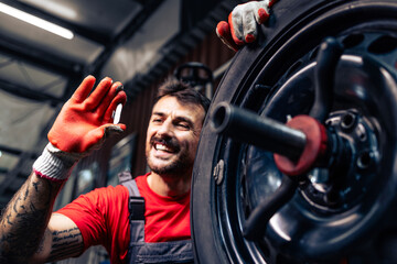 Tire and wheels repair and maintenance. Tire repairman expert holding wheel balancing weight in...