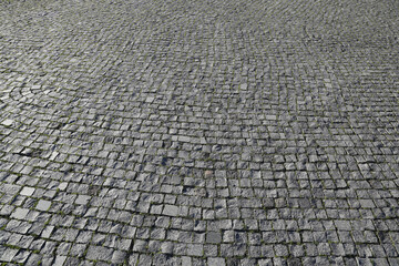 Old square cobble stone with green grass. paving perspective background.Paving stone pavement texture. Cobblestone pavement. stone sidewalk. texture. Cobble stone road cobble texture.  perspective