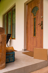 A cardboard box left at the entrance of a wooden country house on a summer day