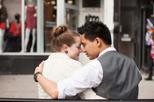 Close-up, backview of couple sitting on bench on city street, Toronto, Ontario, Canada