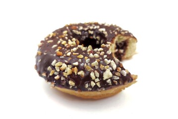 Top view of a bitten, delicious chocolate doughnut sprinkled with nuts, isolated on white background.
