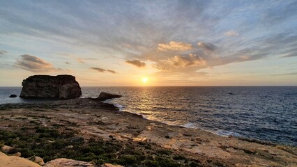 Stunning Sunset over Dwejra Bay, Gozo, Malta: Serene Coastal Landscape with Azure Waters and Golden Horizon