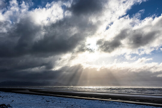 Dramatic view of sun rays shining through the clouds over the Pacific Ocean in Homer; Homer, Alaska, United States of America
