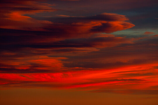 Brilliant red cloud formations create a dramatic, colorful sky; Calgary, Alberta, Canada