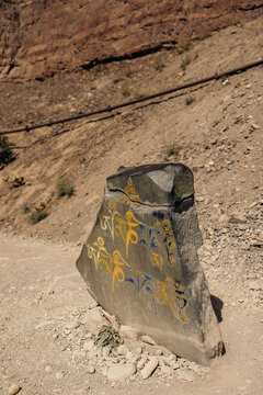 Broken stone with symbols in blue and yellow as a trail marker along the trek path to Phuktal Gompa (Monastary), near Purne, Zanskar, Ladakh; Zanskar, Ladakh, India