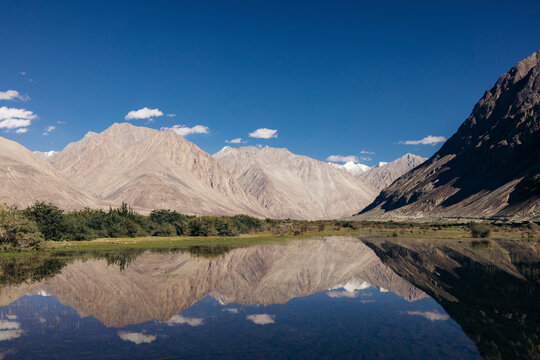 Mountains reflected in mirror image in water in the Nubra Valley; Leh, Ladakh, India