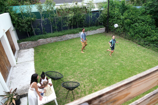 Parents with children (18-22 months, 6-7, 8-9) playing on back yard