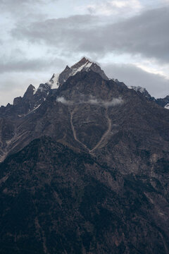 Extreme mountain peaks at the top of a mountain in the Western Himalayas with traces of snow under a cloudy sky; Kupa, Himachal Pradesh, India