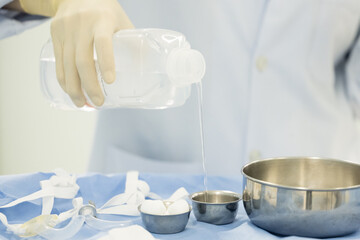 Doctor or nurse hand with surgical set and medical equipment on blue surgical tray inside operating room.Sterile surgical instrument tool equipment for surgery.Infection control.