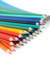 Fototapeta premium A vibrant collection of colored pencils arranged in a row, showcasing a variety of colors including red, blue, green, yellow, and orange against a white background.