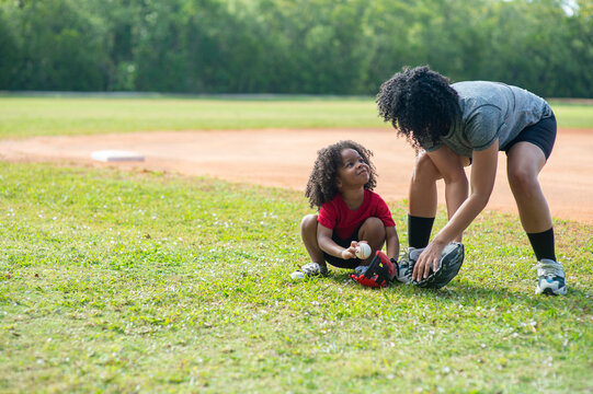Mother spends time with her young daughter at a baseball field; United States of America