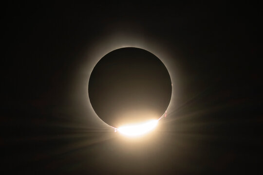 Totality ends with the light of the sun bursting forth from behind the moon. Solar prominences can be seen rising from the sun's surface; Fredricton, New Brunswick, Canada
