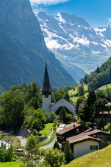 Fototapeta premium Summer landscape of famous alpine village Lauterbrunnen with famous church and Staubbach waterfall. Berner Oberland, Switzerland, Europe
