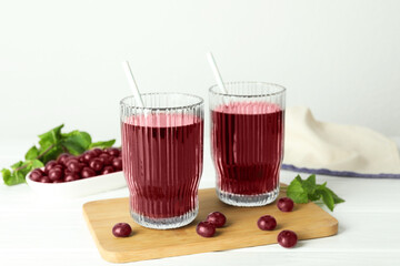 Delicious acai juice in glasses, berries and mint on white wooden table