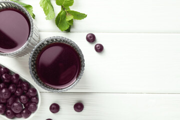Delicious acai juice in glasses, berries and mint on white wooden table, flat lay. Space for text