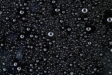 Drops of water on a black surface. The condensate. Top view. Free space.