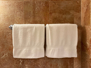 Soft terry towels hanging on tiled wall in hotel bathroom