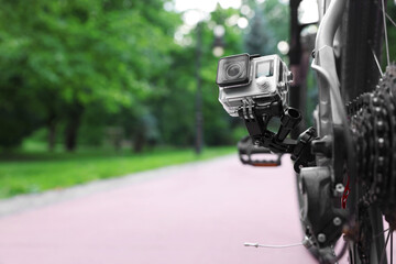 Modern action camera with mount on bicycle outdoors. Space for text