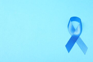 Blue ribbon on color background, top view with space for text. Prostate cancer awareness