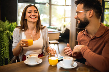 Two friends met at the cafe. Hanging out and drinking orange juice and coffee together.