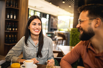 Two friends met at the cafe. Hanging out and drinking orange juice and coffee together.
