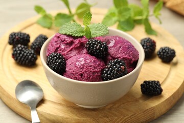 Delicious blackberry sorbet with fresh berries in bowl and spoon on table, closeup
