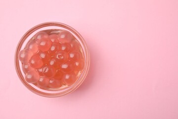 Bright tapioca pearls in bowl on pink background, top view. Space for text