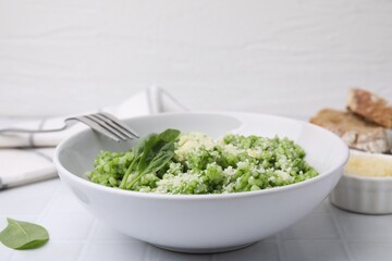 Delicious spinach risotto with parmesan cheese served on white tiled table, closeup