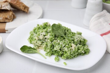 Delicious spinach risotto with parmesan cheese on white tiled table, closeup